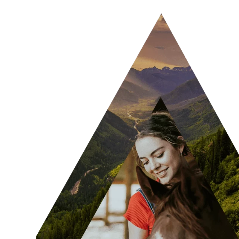 Girl smiling while embracing a horse, set against a mountainous backdrop, symbolizing peace and connection with nature - Turning Winds Residential Treatment Center for Teen Mental Health in the Montana Mountains