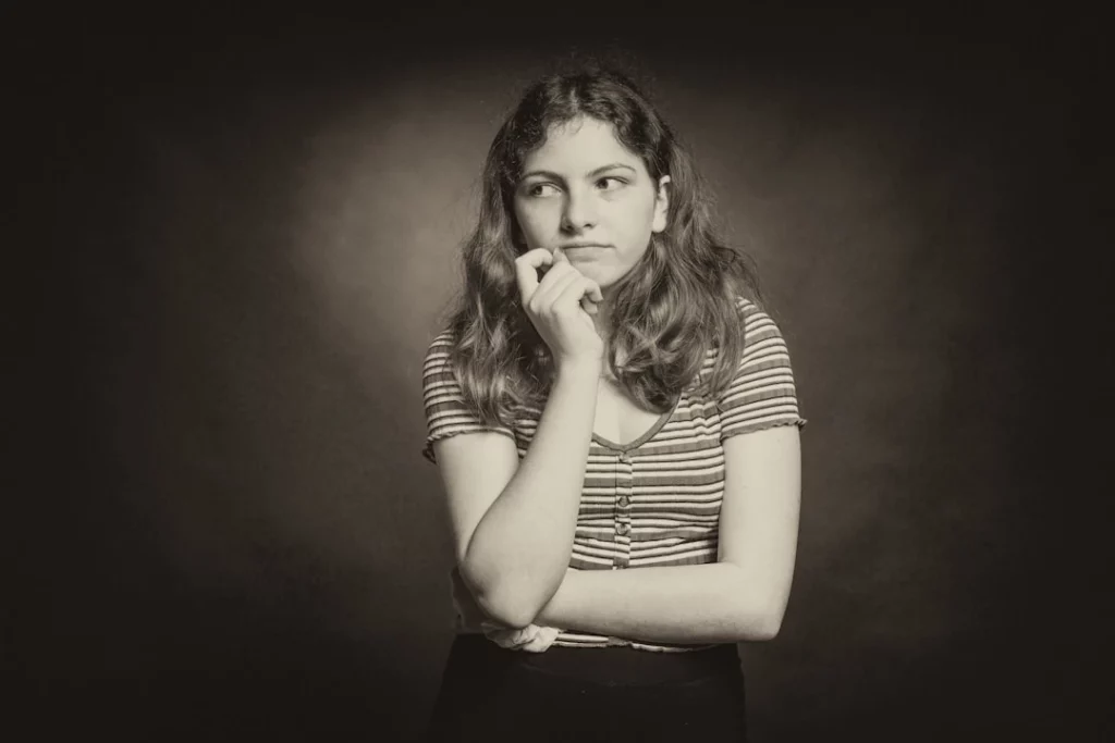 a thoughtful teenage girl thinking about her behavioral issues after her parents were able to secure insurance coverage for her therapy.